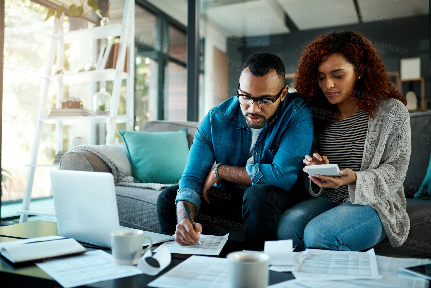 Buy stock photo Shot of a young couple planning their budget together at home