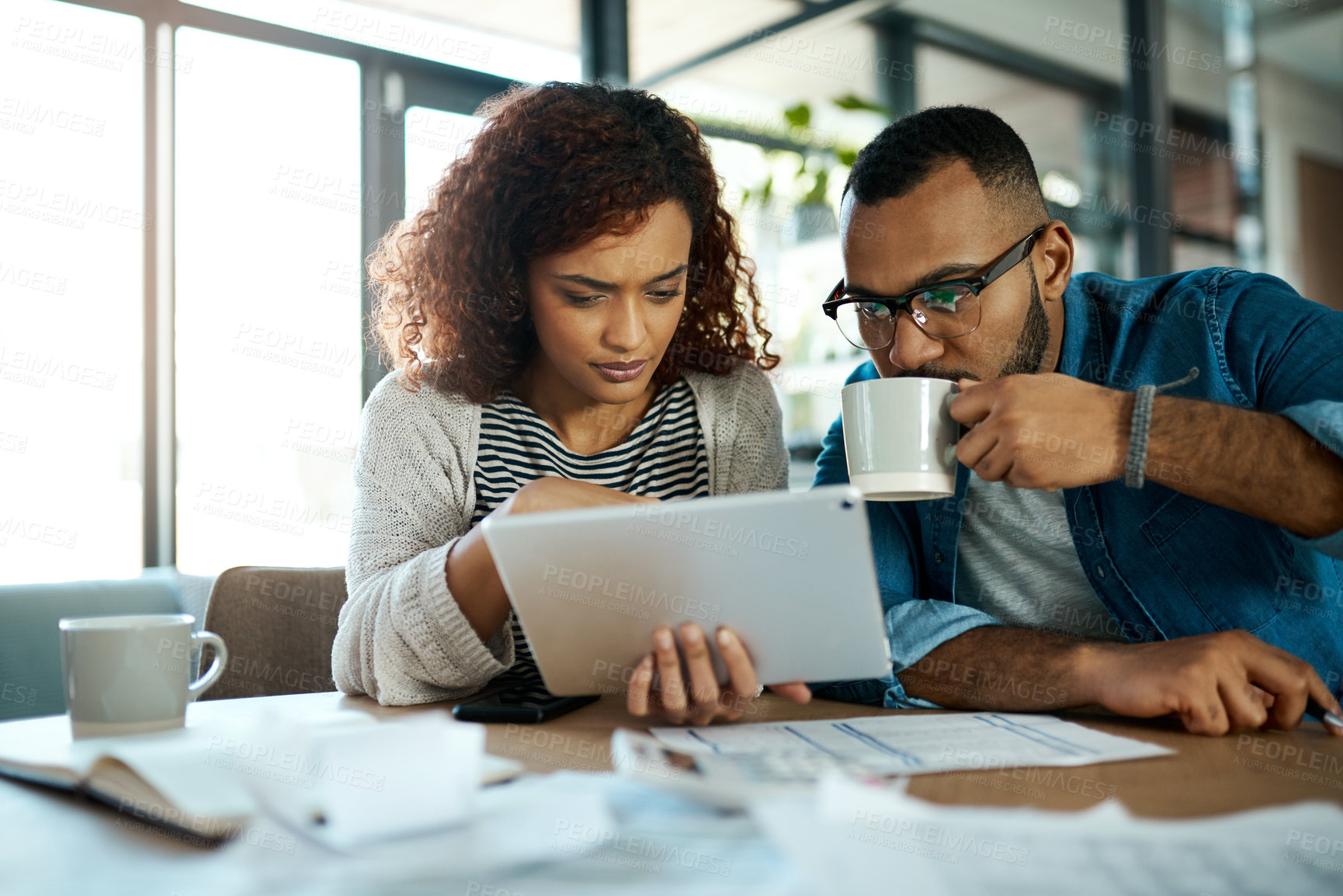 Buy stock photo Shot of a young couple using a digital tablet while planning their budget together at home