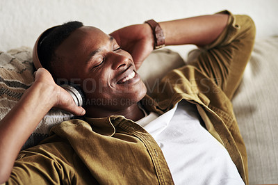 Buy stock photo Cropped shot of a handsome young man smiling with his eyes closed while listening to music on his headphones at home