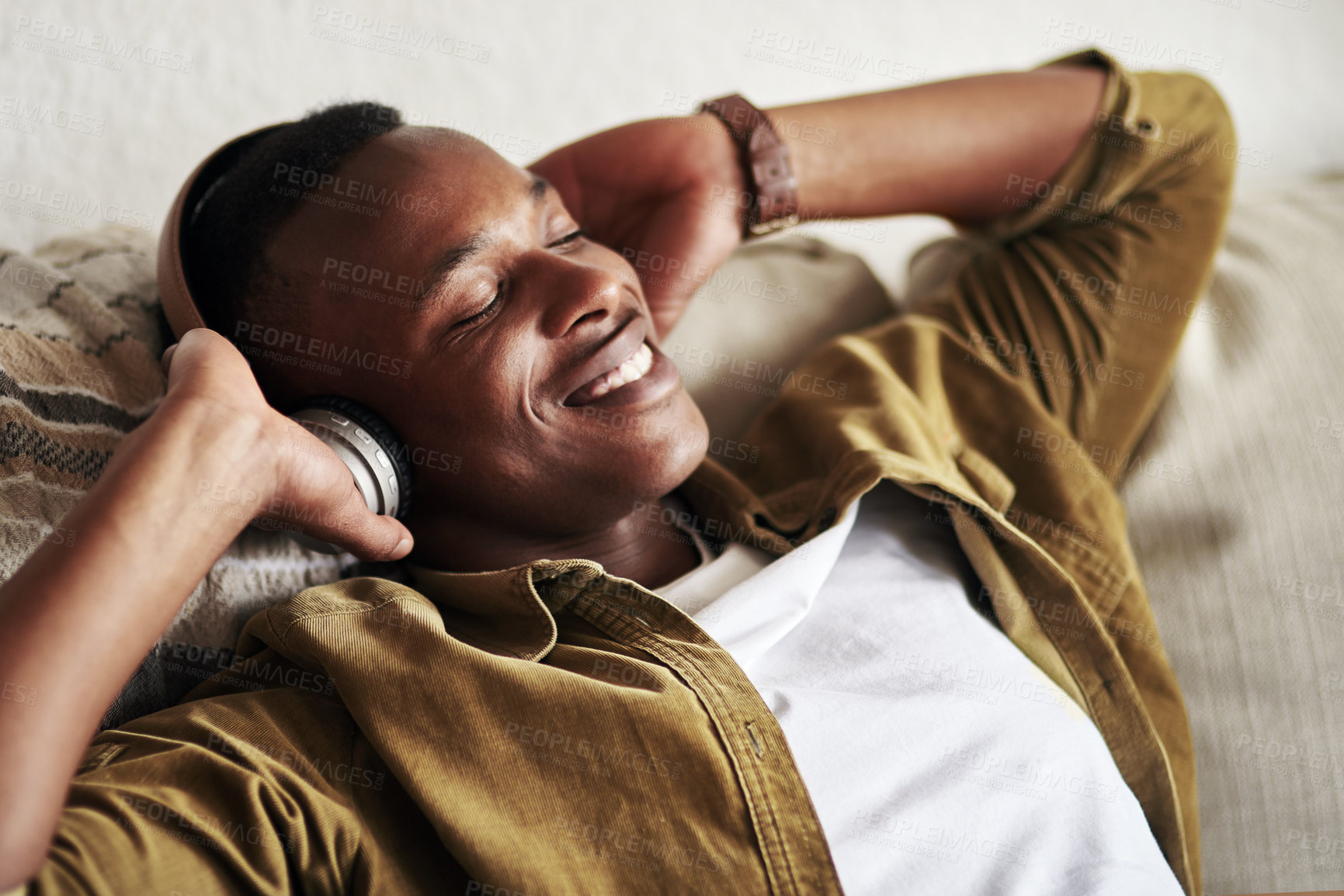 Buy stock photo Cropped shot of a handsome young man smiling with his eyes closed while listening to music on his headphones at home