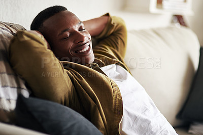 Buy stock photo Cropped shot of a handsome young man smiling with his eyes closed while relaxing on the couch at home