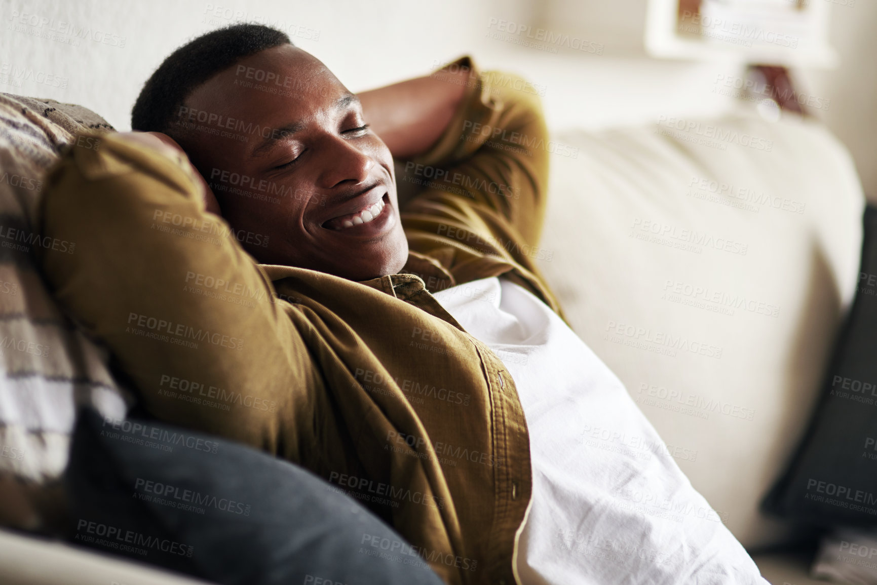 Buy stock photo Cropped shot of a handsome young man smiling with his eyes closed while relaxing on the couch at home