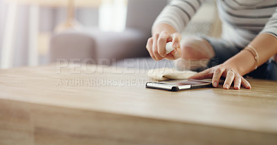 Buy stock photo Woman, hands and cleaning screen of a phone on a wooden table in a home living room with spray bottle. Closeup of a female person with cloth and product to clean dirt, bacteria or dust on smartphone