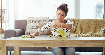 Buy stock photo Shot of a young woman cleaning the table in her living room