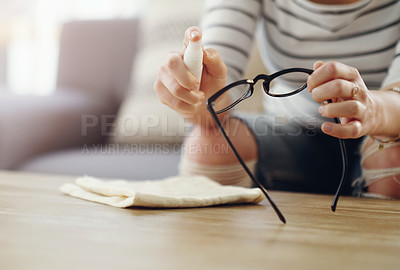 Buy stock photo Cropped shot of an unrecognizable woman cleaning her reading glasses at home