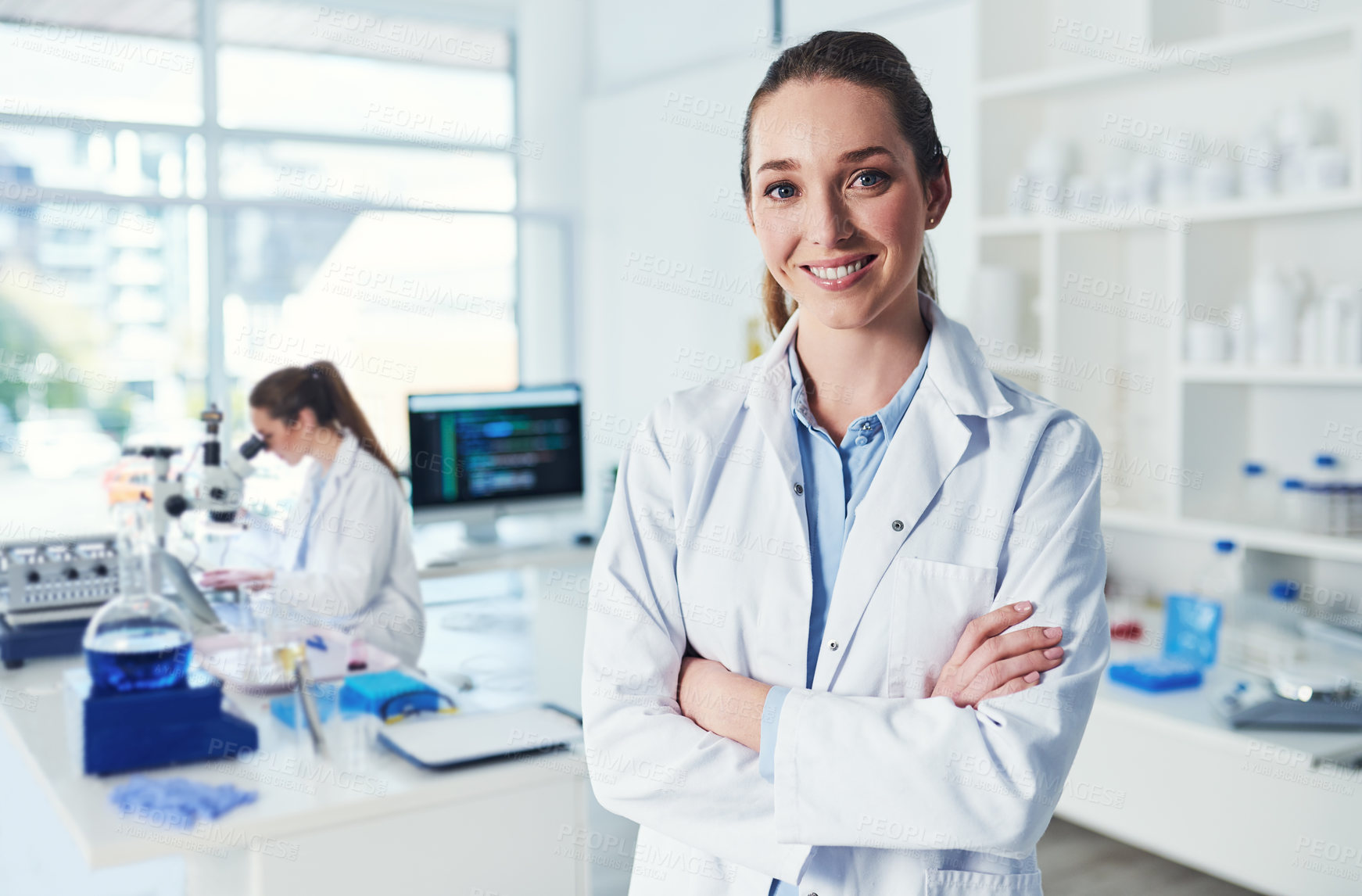 Buy stock photo Portrait of a cheerful young female scientist standing with her arms folded inside of a laboratory during the day