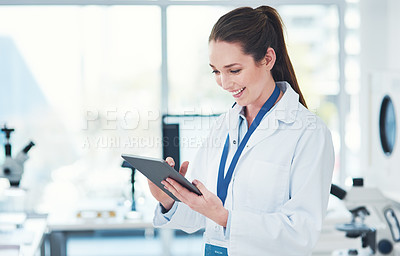 Buy stock photo Cropped shot of a focused young female scientist browsing on a digital tablet inside of a laboratory during the day