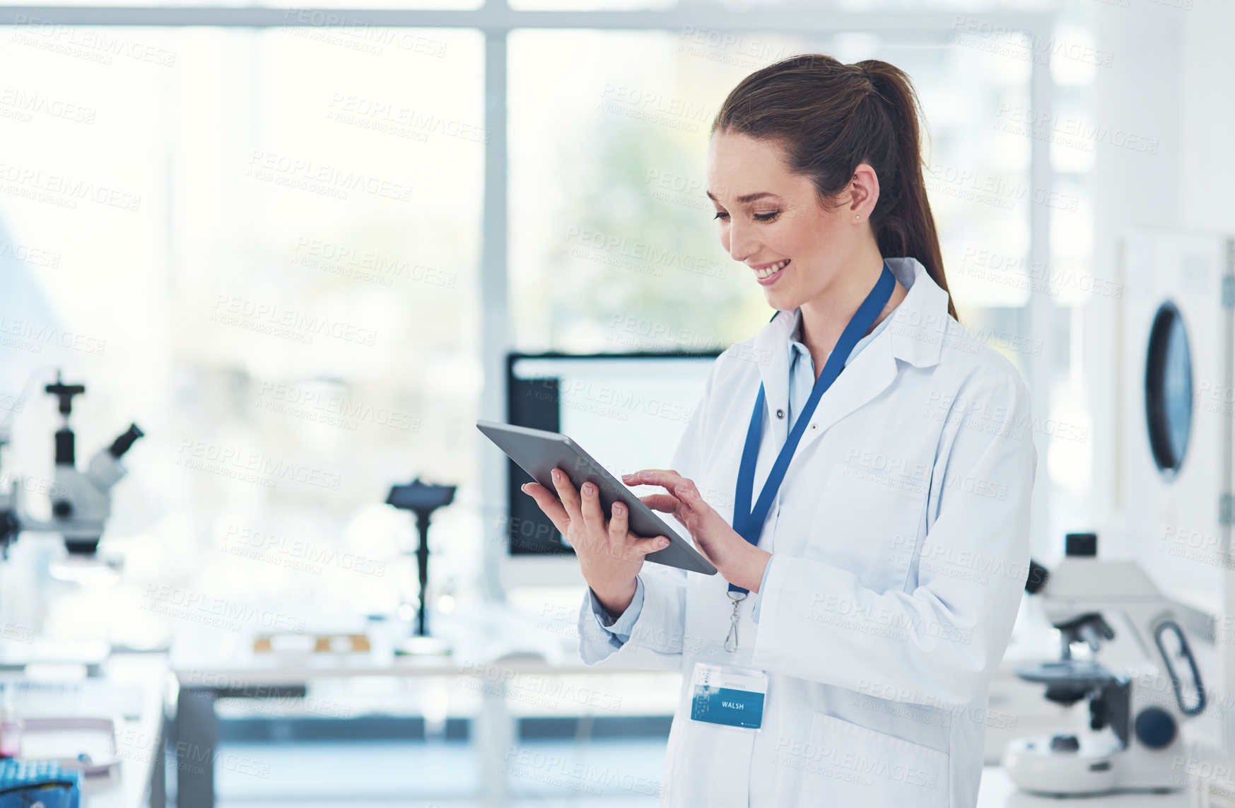 Buy stock photo Cropped shot of a focused young female scientist browsing on a digital tablet inside of a laboratory during the day