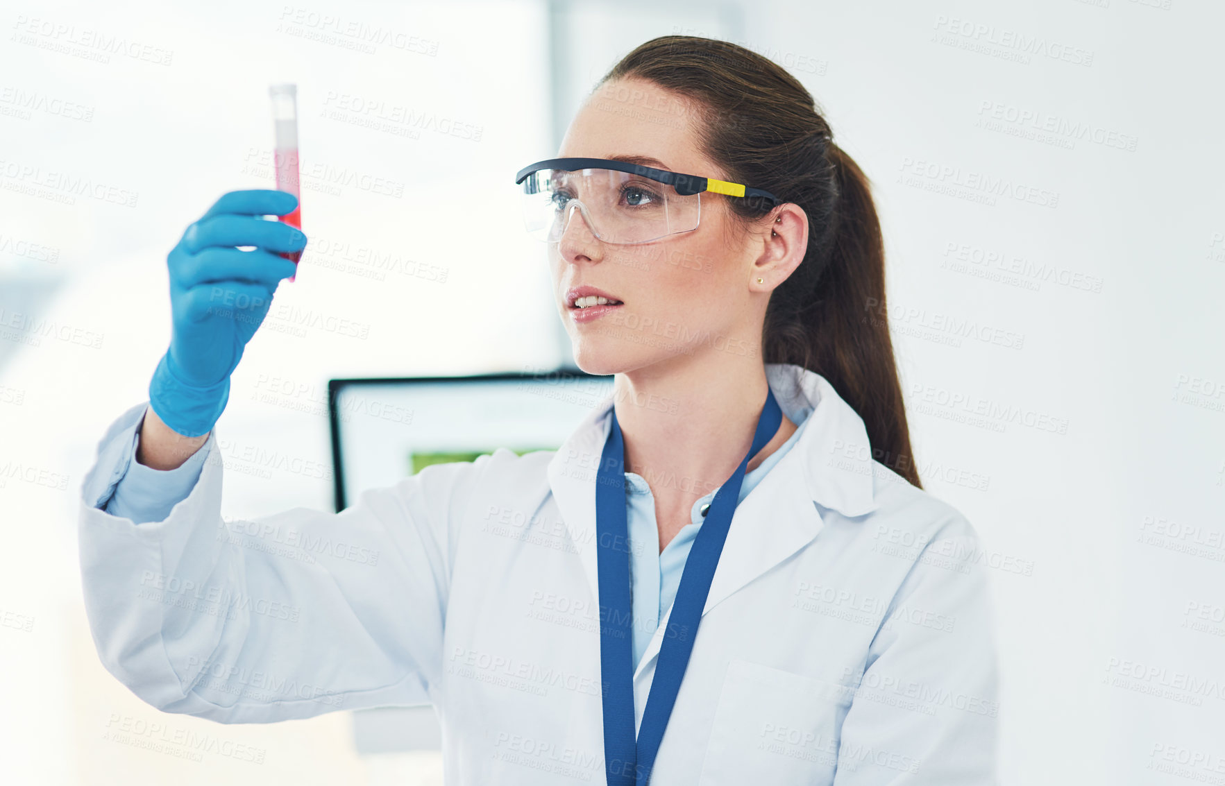Buy stock photo Cropped shot of a focused young female scientist holding up a vile of blood and observing it inside of a laboratory during the day