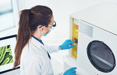 Buy stock photo Rearview shot of an unrecognizable young female scientist wearing protective fave gear while conducting experiments inside of a laboratory