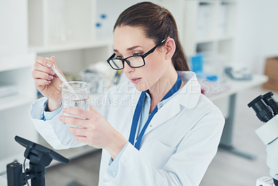 Buy stock photo Cropped shot of a focused young female scientist mixing chemicals together at their desk inside of a laboratory