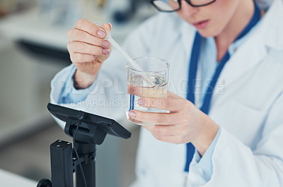 Buy stock photo Cropped shot of a focused young female scientist mixing chemicals together at their desk inside of a laboratory