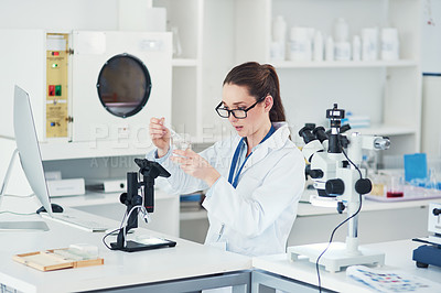 Buy stock photo Cropped shot of a focused young female scientist mixing chemicals together at their desk inside of a laboratory