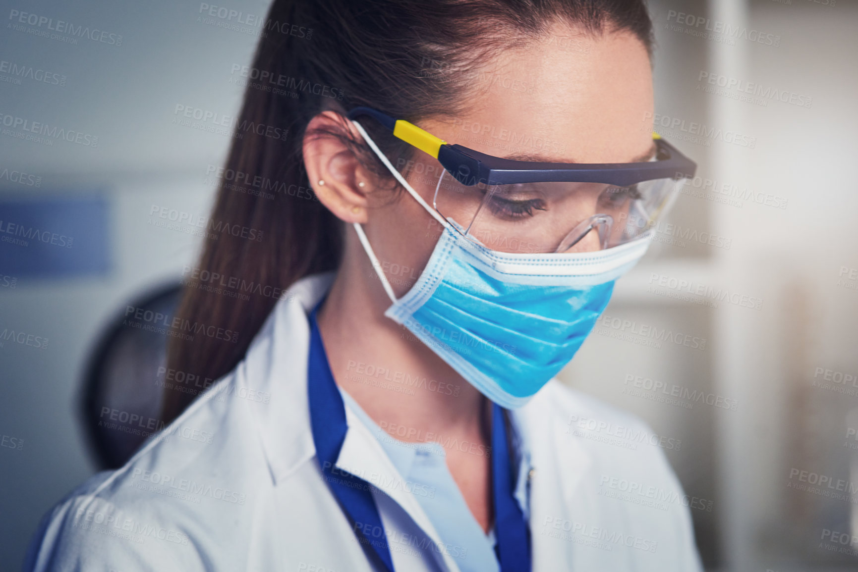 Buy stock photo Closeup of an unrecognizable female scientist wearing a protective face mask while busy working inside of a laboratory