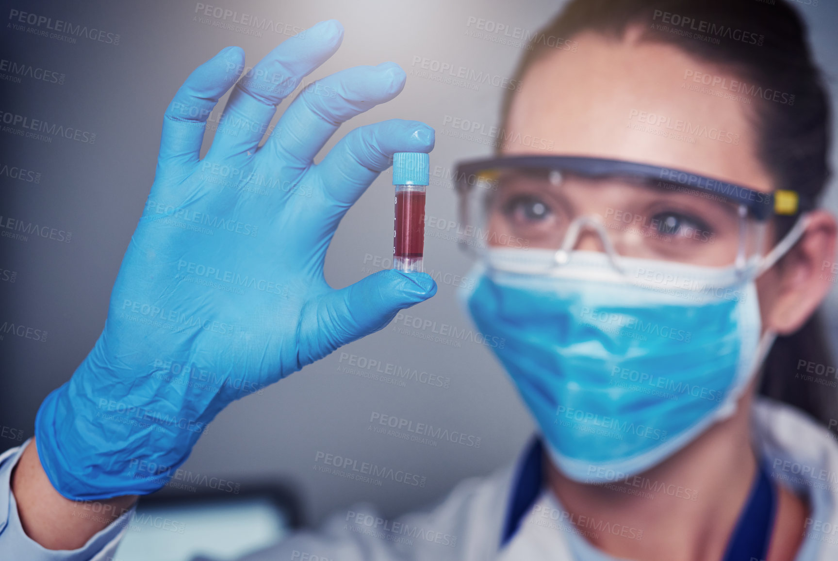 Buy stock photo Closeup of an unrecognizable female scientist wearing a protective face mask and holding up a vile of blood inside of a laboratory