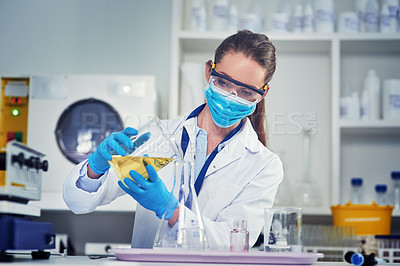 Buy stock photo Cropped shot of an unrecognizable female scientists wearing a protective face mask while mixing chemicals together inside of a laboratory