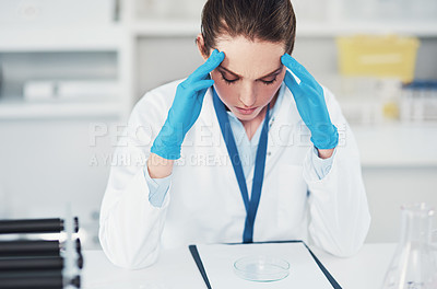 Buy stock photo Cropped shot of a tired young female scientist suffering from a headache while trying to work inside of a laboratory