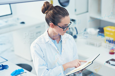 Buy stock photo Cropped shot of a focused young female scientist reading from her notebook inside of a laboratory