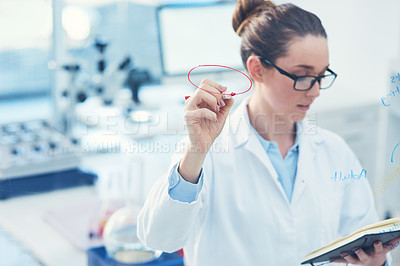 Buy stock photo Cropped shot of a focused young female scientist making notes in a book inside of a laboratory
