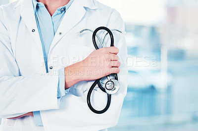 Buy stock photo Cropped shot of an unrecognizable doctor holding a stethoscope in their hand while standing inside of a hospital during the day