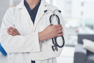 Buy stock photo Cropped shot of an unrecognizable female doctor holding a stethoscope while standing with her arms crossed in her office