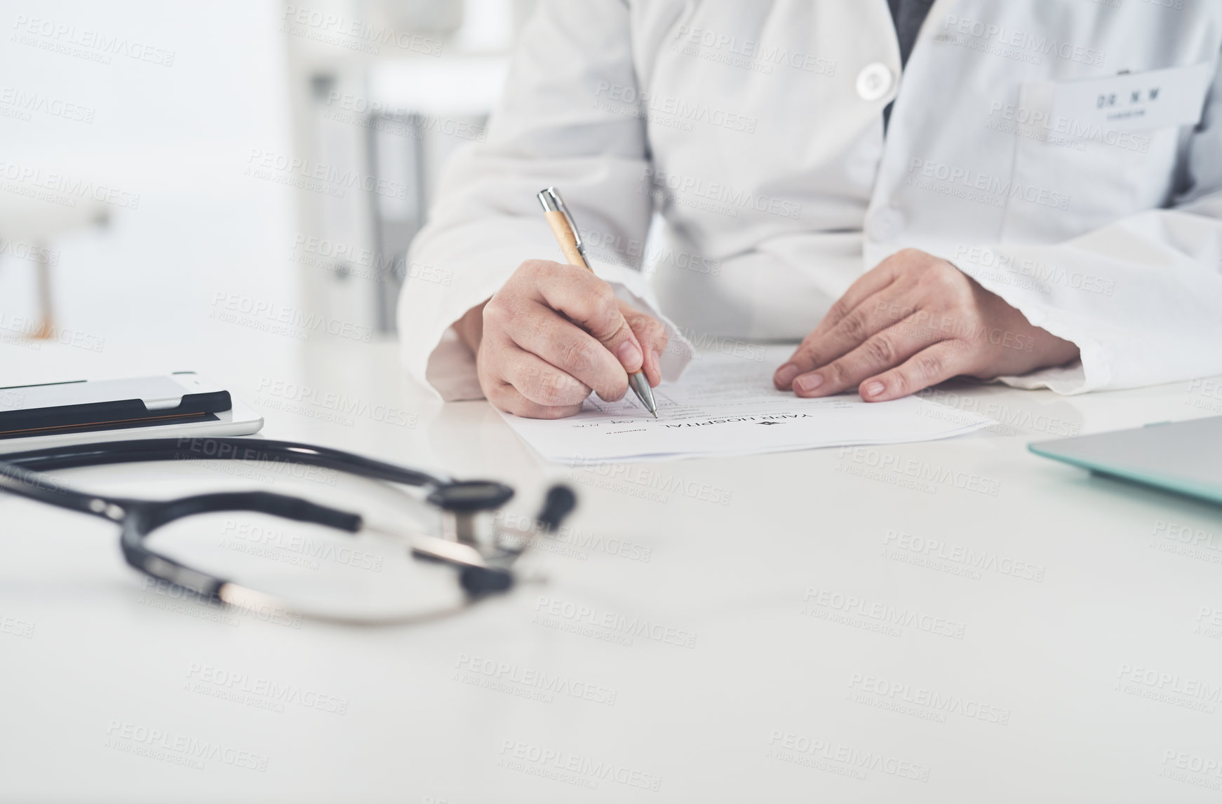 Buy stock photo Cropped shot of an unrecognizable female doctor writing on a document while working in her office