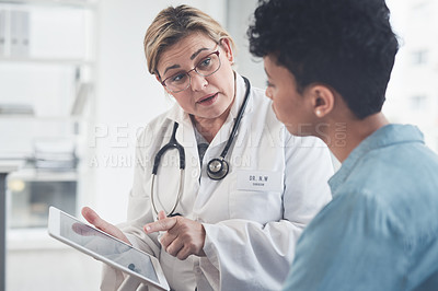 Buy stock photo Cropped shot of an attractive young female doctor using a digital tablet while having a discussion with a female patient in her office