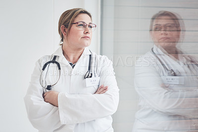 Buy stock photo Cropped shot of an attractive young female doctor looking thoughtful while standing with her arms crossed in her office
