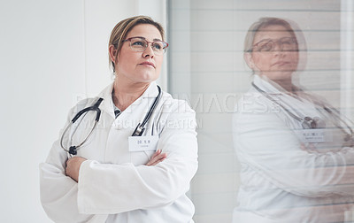 Buy stock photo Cropped shot of an attractive young female doctor looking thoughtful while standing with her arms crossed in her office