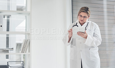 Buy stock photo Cropped shot of an attractive young female doctor using a digital tablet while standing in her office