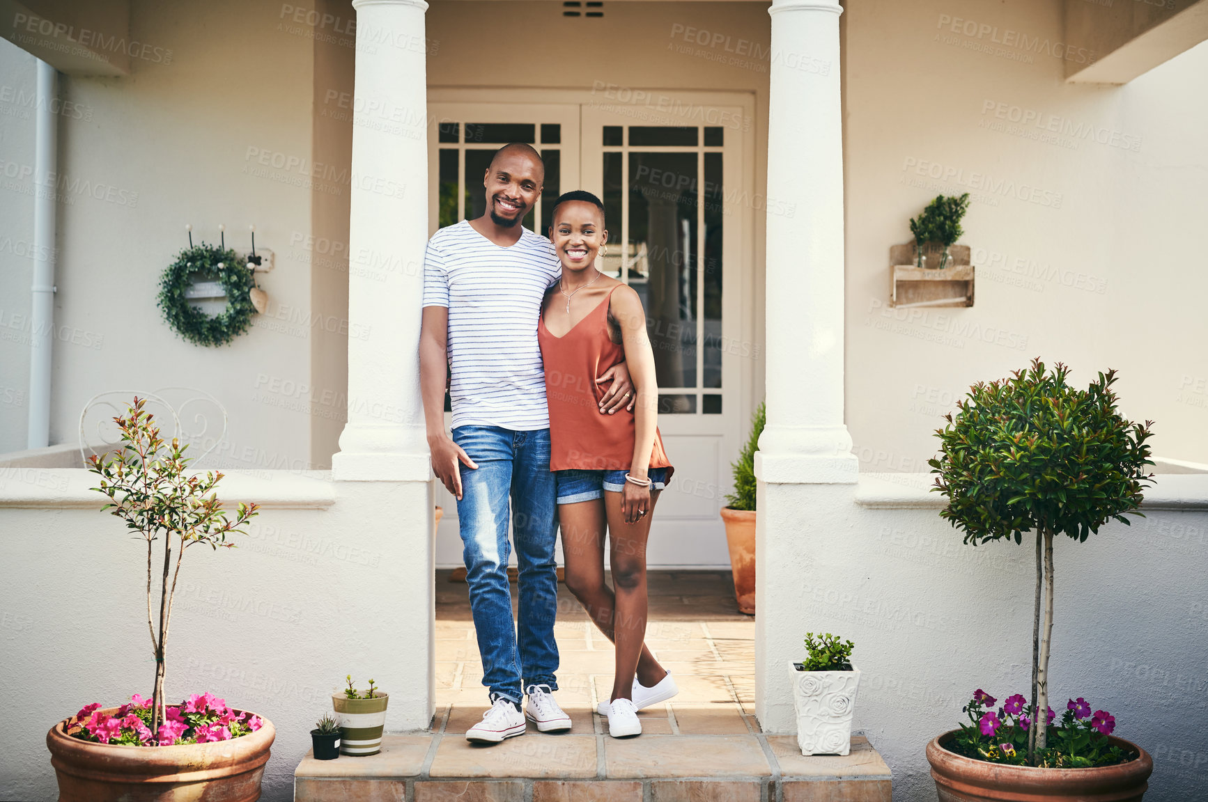 Buy stock photo Shot of a happy young couple standing on their front porch