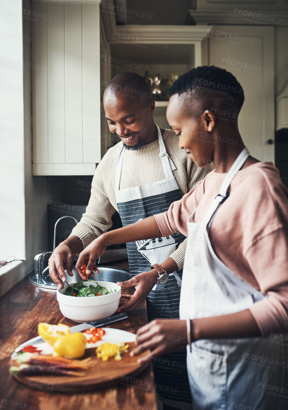 Buy stock photo Cropped shot of an affectionate young couple preparing dinner in their kitchen