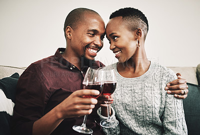 Buy stock photo Shot of a happy young couple drinking wine and relaxing together at home