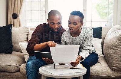 Buy stock photo Shot of a young couple using a digital tablet while  going over their bills and finances at home