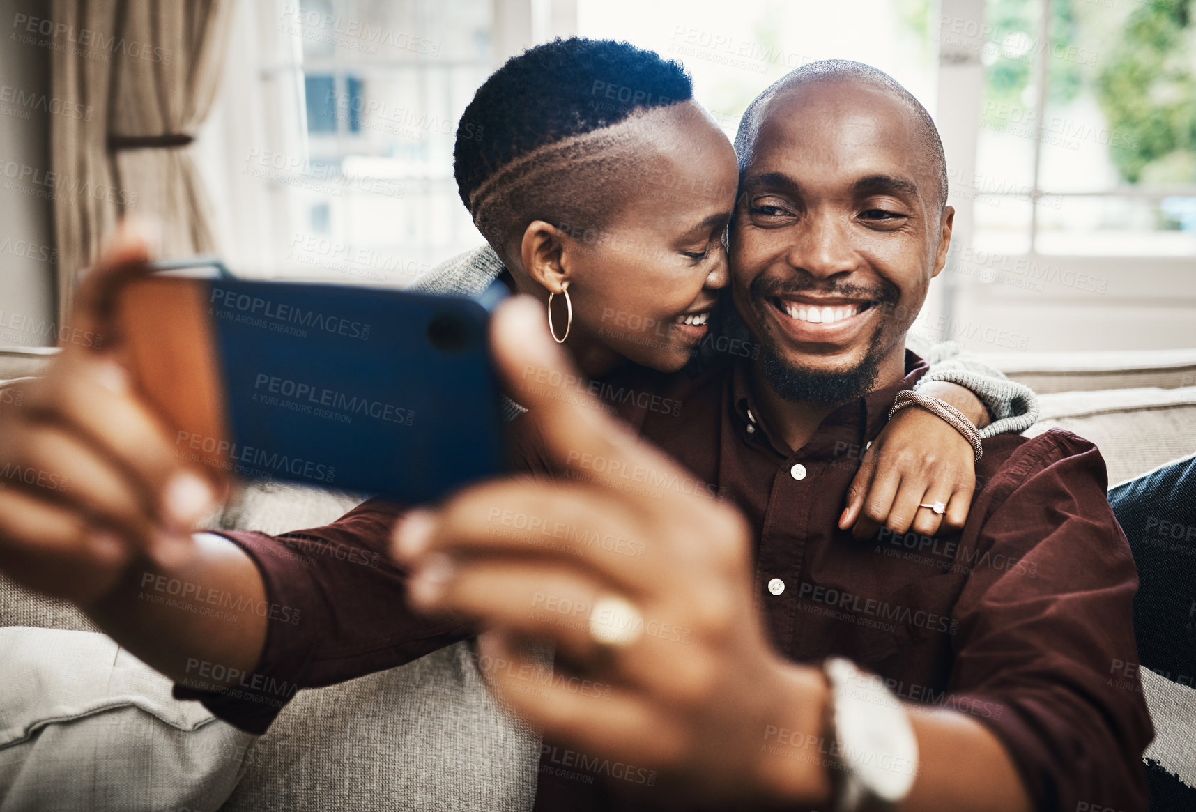 Buy stock photo Shot of a happy and affectionate young couple taking selfies together at home