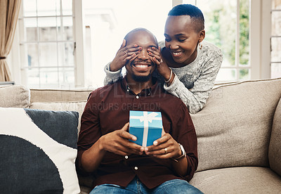 Buy stock photo Shot of a beautiful young woman surprising her husband with present at home