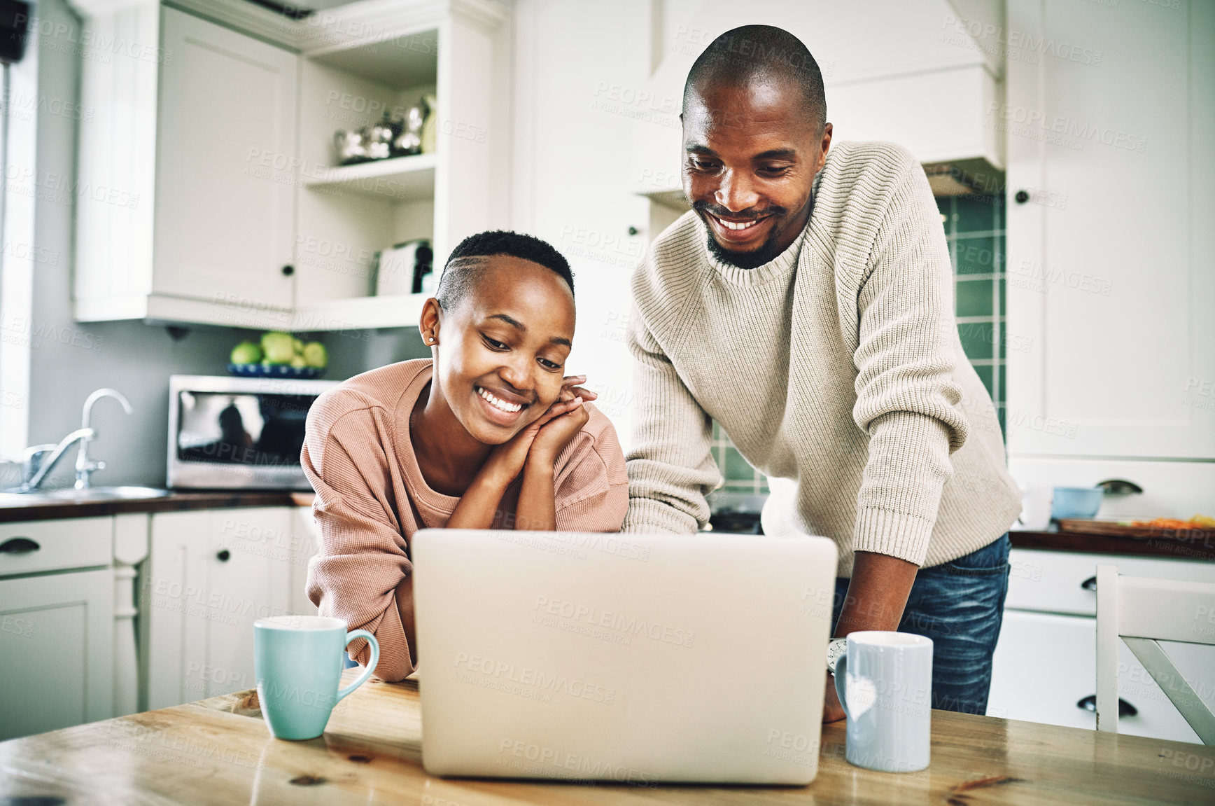 Buy stock photo Shot of a happy young couple using a laptop while relaxing together at home
