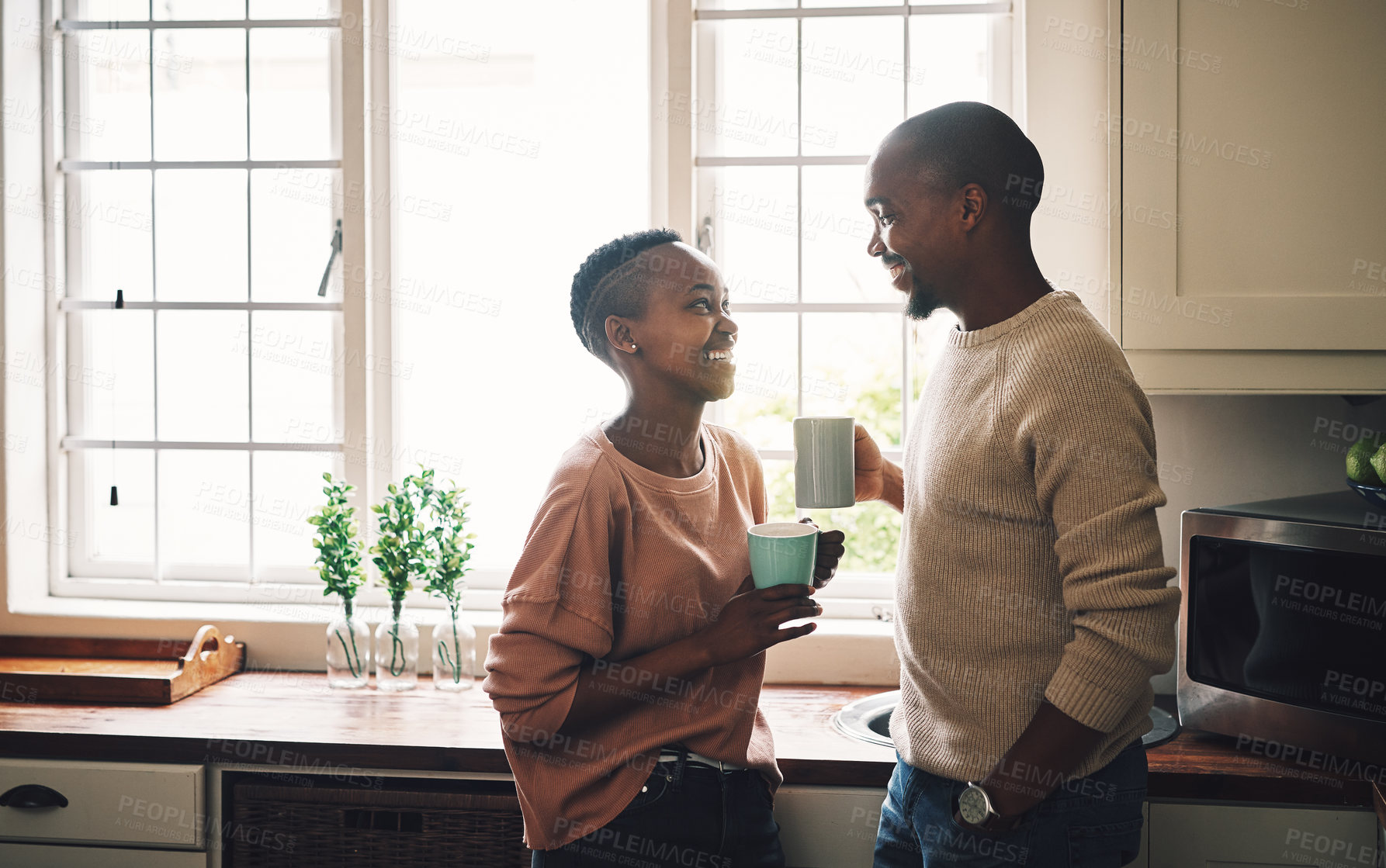Buy stock photo Shot of a happy young couple drinking coffee and spending time together at home