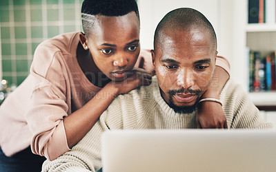 Buy stock photo Shot of a young couple using a laptop while relaxing together at home