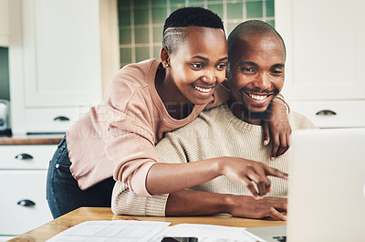 Buy stock photo Shot of a happy young couple using a laptop while relaxing together at home