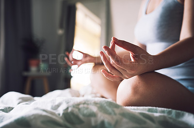 Buy stock photo Cropped shot of an unrecognizable woman meditating while sitting on her bed in her bedroom at home