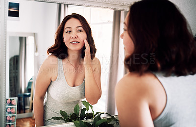 Buy stock photo Cropped shot of an attractive young woman inspecting her face while standing in front of the mirror in her bedroom at home