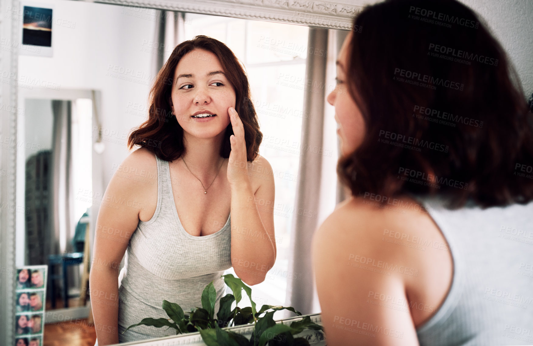 Buy stock photo Cropped shot of an attractive young woman inspecting her face while standing in front of the mirror in her bedroom at home