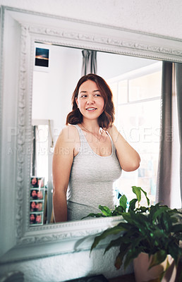 Buy stock photo Cropped shot of an attractive young woman admiring herself while standing in front of the mirror in her bedroom at home