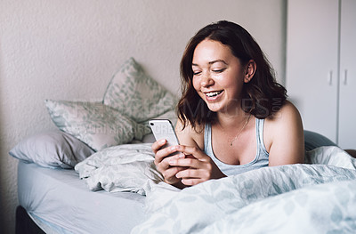 Buy stock photo Shot of an attractive young woman laughing while using a smartphone in her bedroom at home