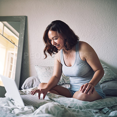 Buy stock photo Full length shot of an attractive young woman smiling while using a laptop in her bedroom at home