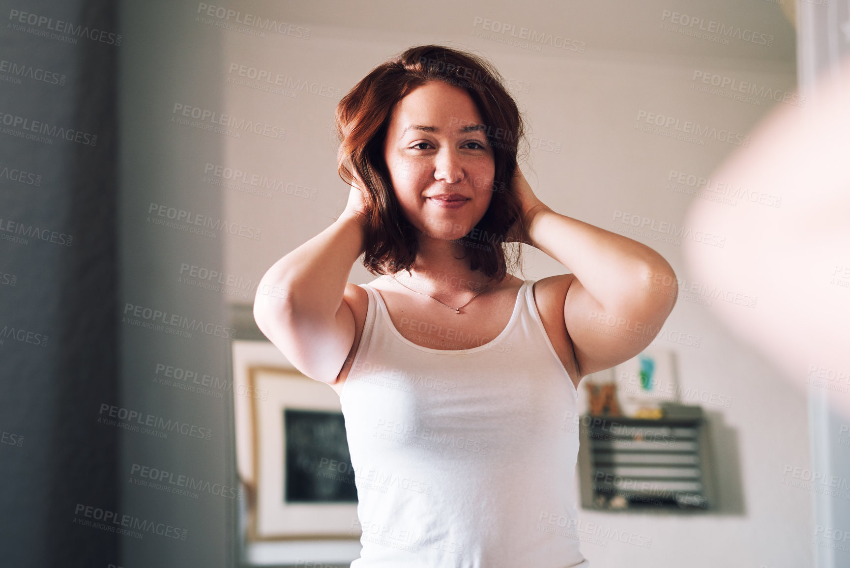 Buy stock photo Cropped shot of an attractive young woman admiring her hair while standing in front of the mirror in her bedroom at home