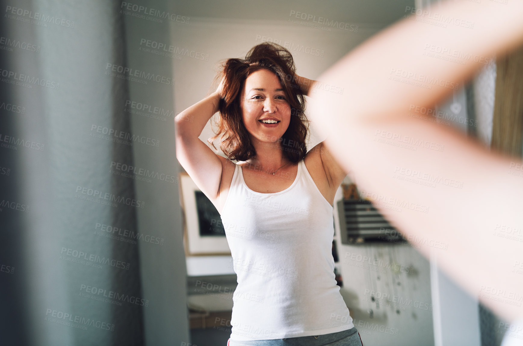 Buy stock photo Cropped shot of an attractive young woman admiring her hair while standing in front of the mirror in her bedroom at home