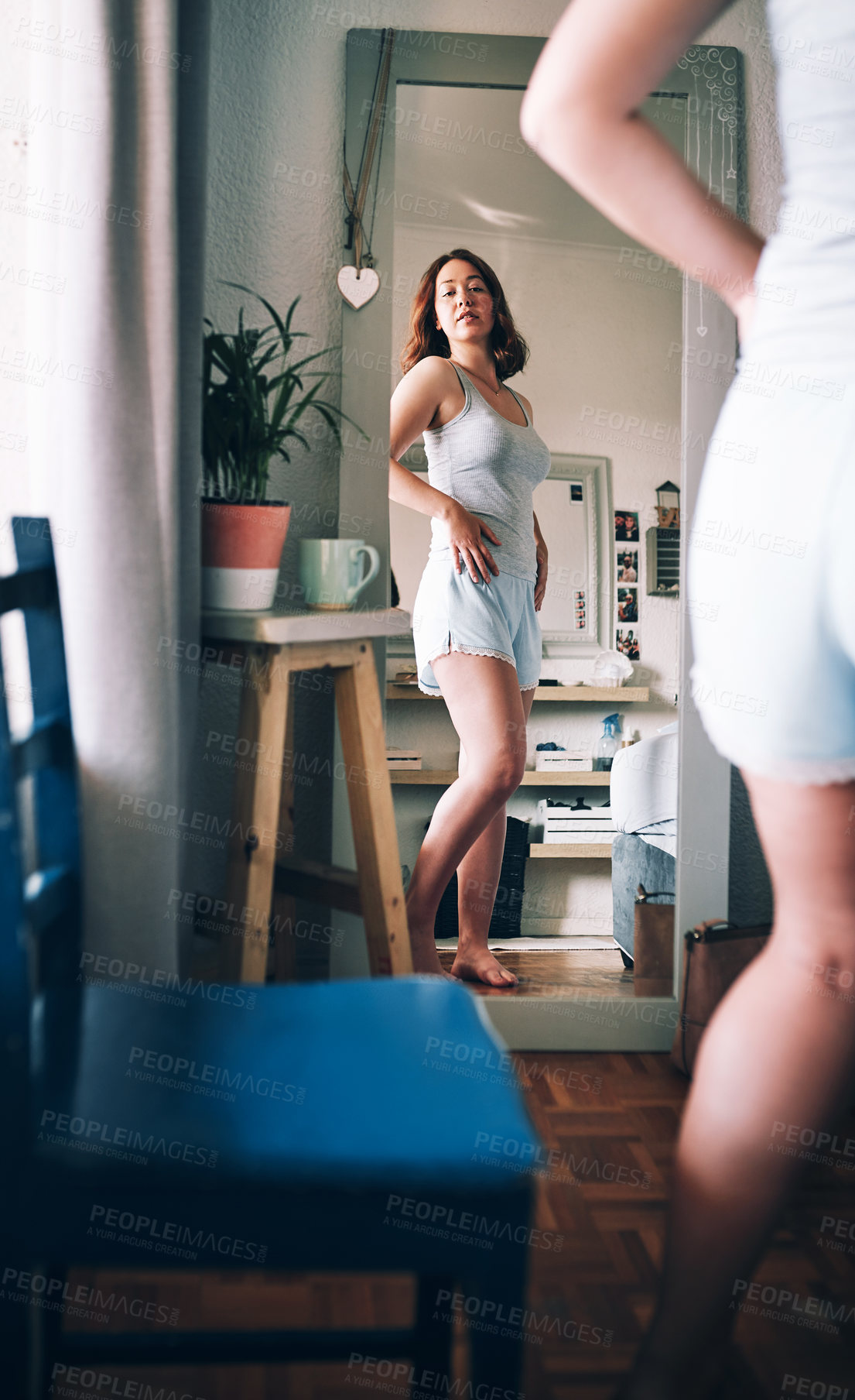 Buy stock photo Cropped shot of an attractive young woman inspecting herself while standing in front of the mirror in her bedroom at home