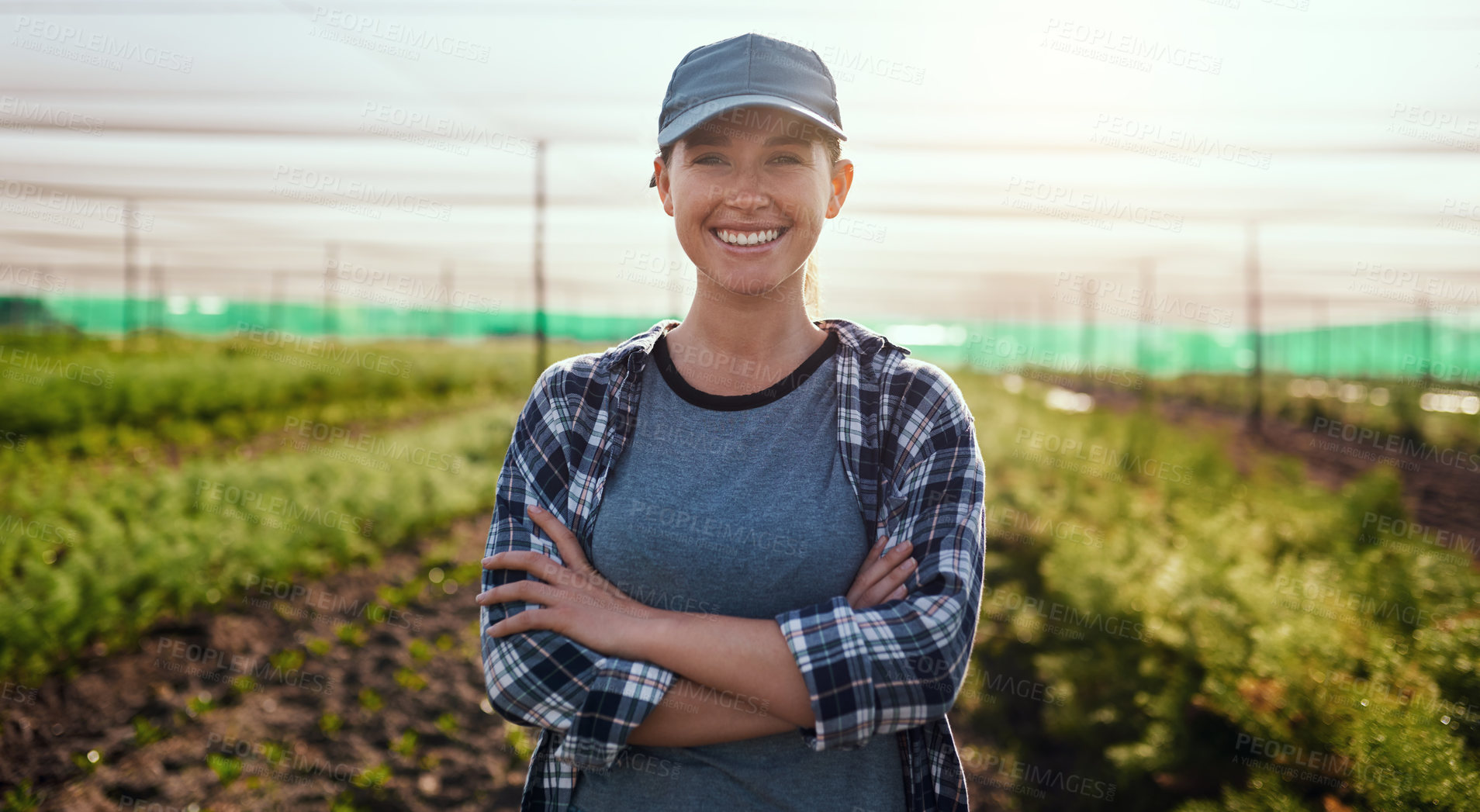 Buy stock photo Cropped portrait of an attractive young female farmer standing with her arms crossed while working on the farm